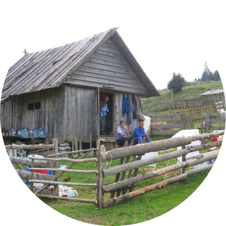 Shepherd family in front of their wooden home. 